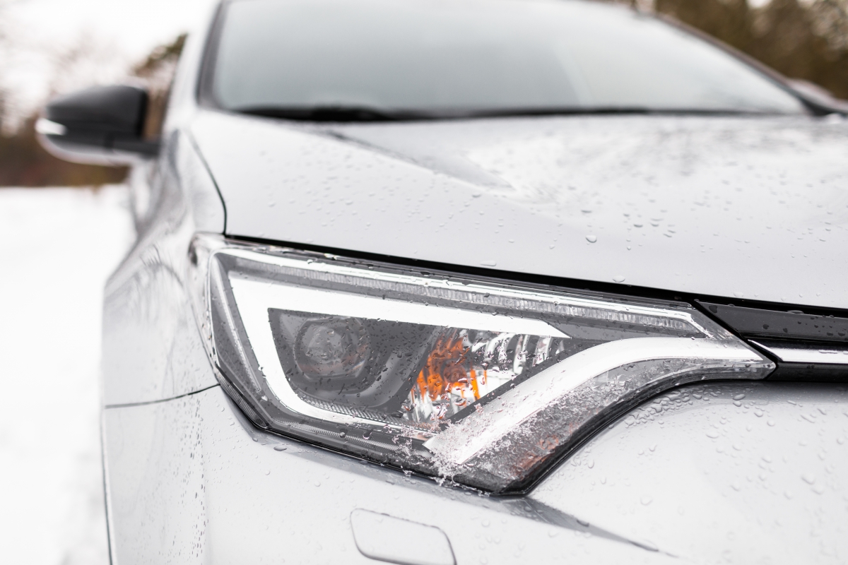 Closeup of a Vehicle Headlight and Hood in the Snow