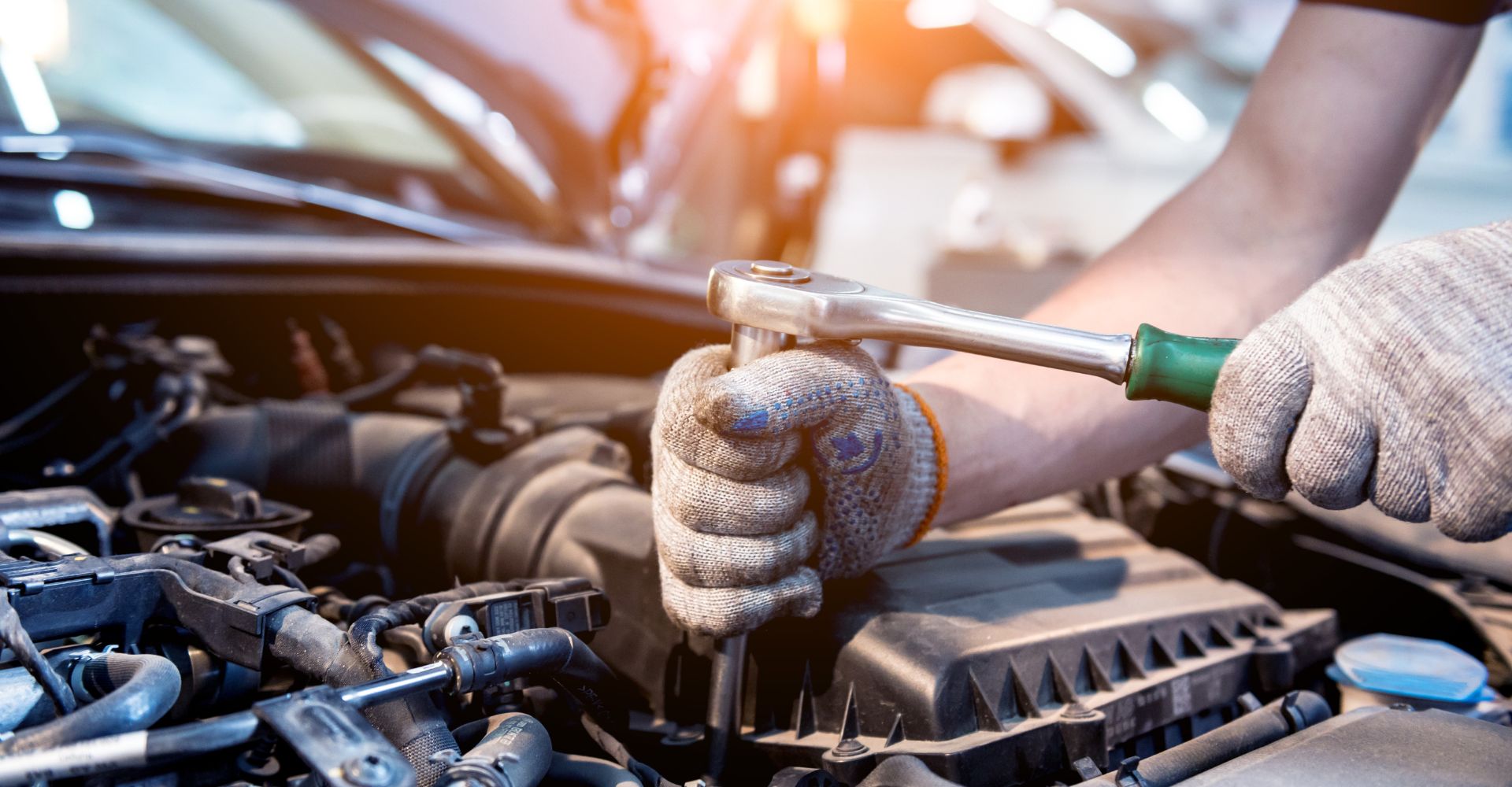 mechanic using a rachet on a car engine