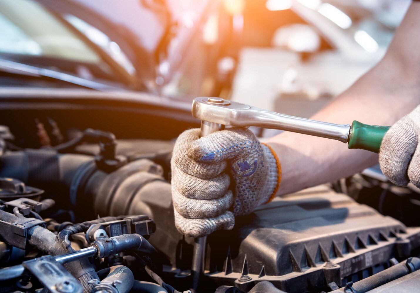 mechanic using a rachet on a car engine