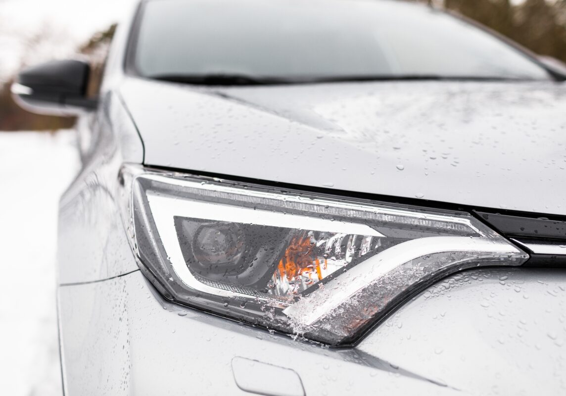 Closeup of a Vehicle Headlight and Hood in the Snow